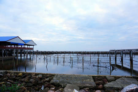 Long simple wooden jetty leading into blue ocean in the gulf of Thailand with sunsetの写真素材
