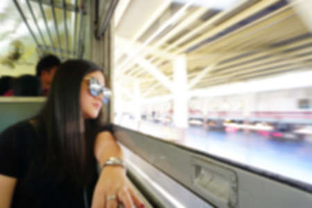 Blur young woman sitting in the public transportation moving train. Looking outside of windowの写真素材