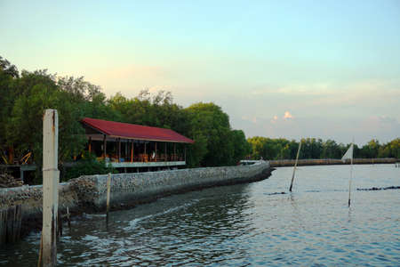 Breakwater, concrete sea wall and building next to oceanの写真素材