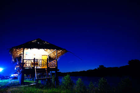 Straw house near small lake with sky in nightime, countryside of Thailandの写真素材