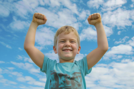 Excited Little Boy Raises Arms in Joyful Celebrationの素材