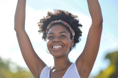 Portrait of a beautiful young african american woman with arms raisedの素材
