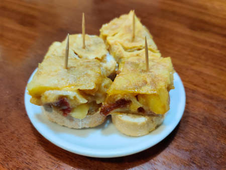 four spanish potato omelette tapas on white plate on wooden tableの写真素材