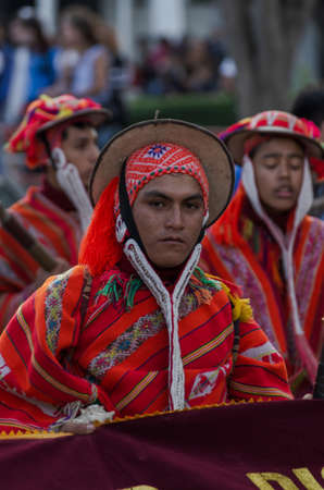 Caraz, Peru, July 19, 2010: serious man in orange typical andean costume carrying banner in popular celebrationのeditorial素材