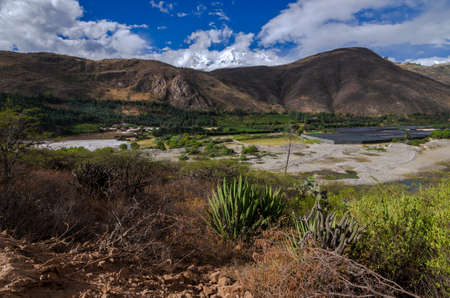 mining debris in the santa river in callejon de huaylas with snowy mountain in the background and cactus in the foregroundの写真素材
