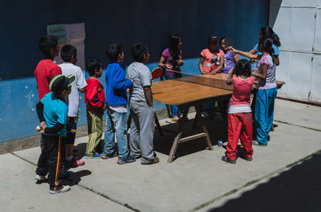 Yungay, Peru, August 6, 2014: group of humble children with latin features playing ping pong at a homemade table made with a board and easelsのeditorial素材