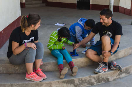 Yungay, Peru, August 8, 2014: ngo cooperating man and woman playing with boy and girl on four grated sitting on the floor happilyのeditorial素材