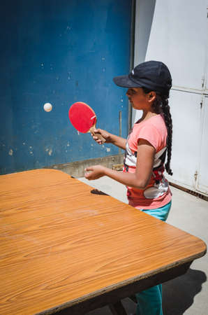 Yungay, Peru, August 8, 2014: portrait of girl in cap playing ping pong with racket in hand giving ballのeditorial素材