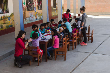 Yungay, Peru, August 4, 2014: Humble boys and girls around a table doing crafts with paint, paper, and glue accompanied by adults, horizontallyのeditorial素材