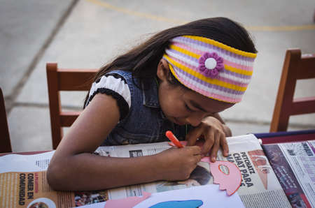 Yungay, Peru, August 4, 2014: portrait of small latin girl with concentrated headband making a craft maskのeditorial素材