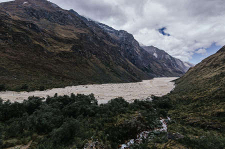 Remains of an avalanche in the valley next to vegetation, in the trekking of the Santa Cruz gorge between mountains, Peruの写真素材