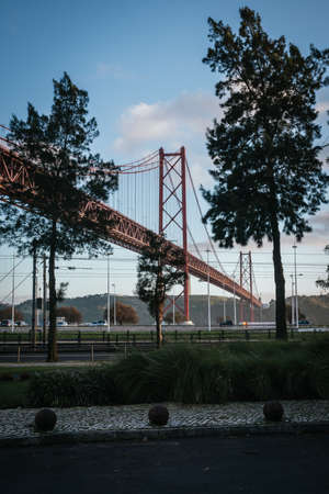view of the 25 de abril bridge in lisbon from the shore framed by trees, verticaの写真素材