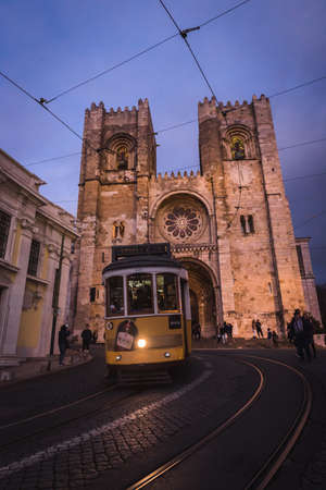 Lisbon, Portugal, January 24, 2020: SE cathedral with old yellow tram passing by at blue hourの写真素材