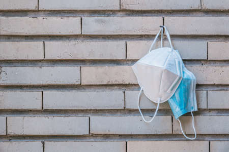 surgical mask and ffp2 k95 hanging on a nail disinfecting on a vintage brick wall, horizontalの写真素材