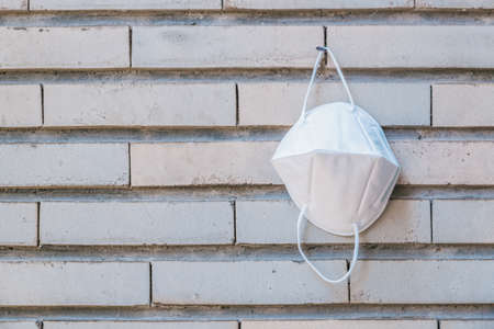 ffp2 k95 face mask hanging on a nail disinfecting on a vintage brick wall, horizontal