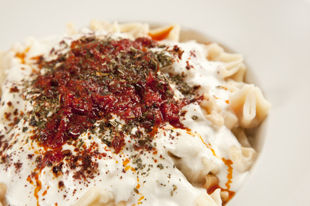 Turkish Manti manlama on plate with red pepper, tomatoes sauce, yogurt and mintの写真素材