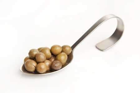 green olive on the spoon isolated white backgroundの写真素材