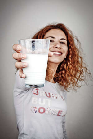 happy young woman with milk over grey backgroundの写真素材