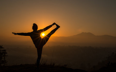 Female doing Yoga exercise for good health early morning with gloomy Sunrise  at Kathmandu, Nepalの写真素材