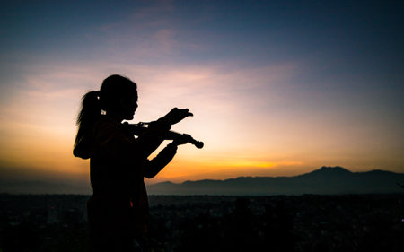 Silhouette of woman playing violin on the background of Sunrise in Kathmandu, Nepal.の写真素材