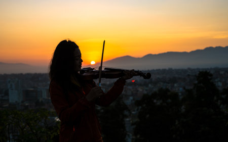 Silhouette of woman playing violin on the background of Sunrise in Kathmandu, Nepal.の写真素材