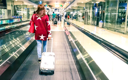 Young woman with luggage on escalator at airport, Seoul, South Korea.の写真素材