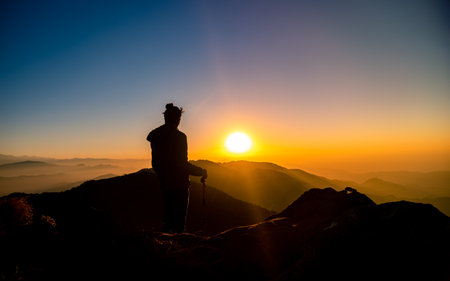 Silhouette of photographer on the peak of the mountain at sunrise from Bethanchowk hill, Nepal.の写真素材