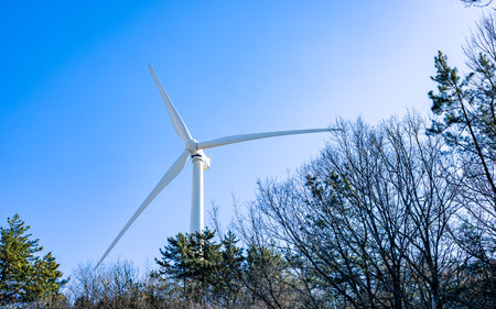 Wind Turbines on Snowy Hillside in Winter Landscape with Blue Sky in South Korea.