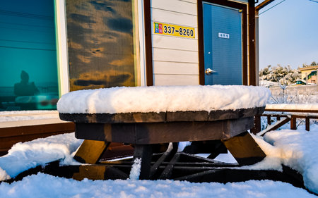 Snow covered bench on the platform of a train station in winter.