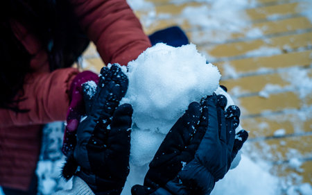 Close-up of female hands in gloves holding snowflakes outdoors.の写真素材