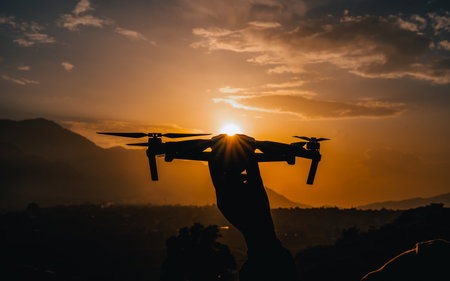 Silhouette of drone in hand with sunset sky background. Digital photography.