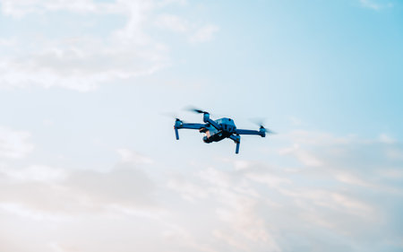 Drone with digital camera flying in the blue sky with white cloudsの写真素材