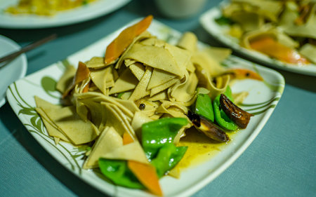 Closeup of a plate of spaghetti with meat and vegetables on a tableの写真素材