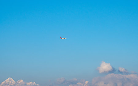 Plane flying in the blue sky with white clouds on sunny day