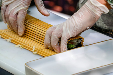 Japanese chef preparing sushi rolls in a restaurant, closeup of handsの写真素材