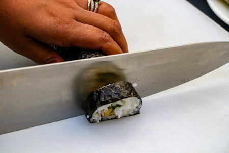 Hands of chef cutting a piece of sushi with a knife.の写真素材