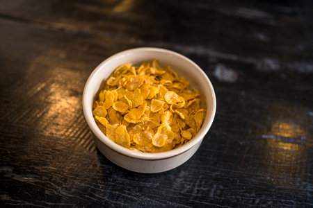 Cornflakes in a bowl on wooden background. Selective focus.