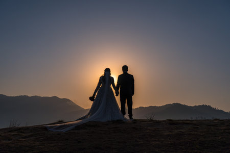 Silhouette of the bride and groom at sunrise in the mountainsの写真素材