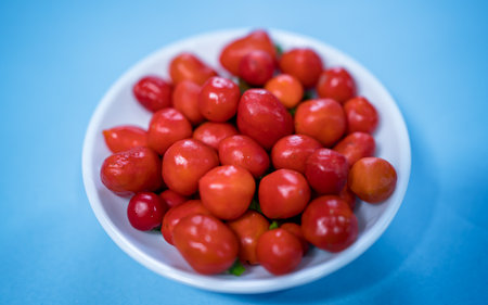 red cherry in a white bowl on blue background, selective focusの写真素材