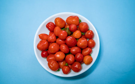 Red cherry tomatoes on a plate on a blue background, top viewの写真素材