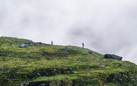 Climbers on the top of a mountain in the clouds.