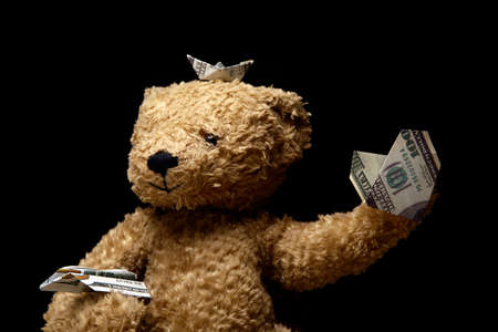 image of toy bear holding money on dark backgroundの写真素材