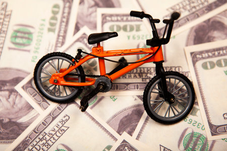Toy bicycle on a background of dollar bills. The concept of buying a bicycle.