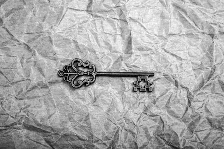 Vintage key on crumpled paper backgroundの写真素材