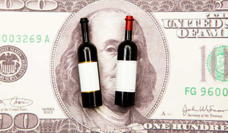 Two wine bottles on the background of one hundred dollar billsの写真素材
