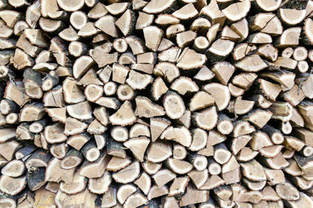 Background of dry chopped oak firewood logs stacked up on top of each other in a pileの写真素材