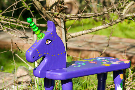 A handmade violet rocker horse toy standing in a garden.の写真素材