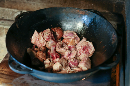 Lamb meat fried in a cast iron cauldron on open fire outdoors.の写真素材