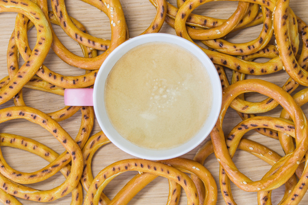 Coffee in a light pink cup on a wooden board with bagels. View from aboveの写真素材