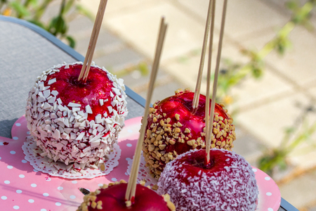 Homemade gourmet caramelized red apples with nuts and chocolate drizzle sitting on large pink plate.の写真素材